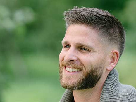 Lächelnder, schöner Mann mit vollem Haar in der Natur