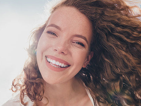 Frau mit lockigen, schuppenfreien Haaren lächelt in die Kamera