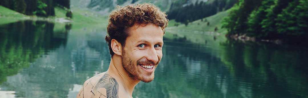 Lachender Mann vor klarem See in den Bergen