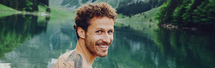 Lachender Mann vor klarem See in den Bergen