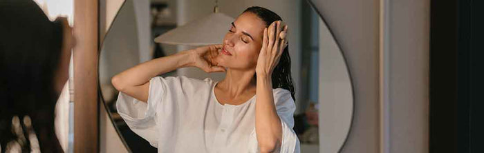 Frau verteilt Haarpflege im nassen Haar und massiert die Kopfhaut