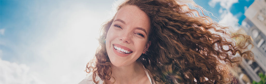 Frau mit lockigen, schuppenfreien Haaren lächelt in die Kamera